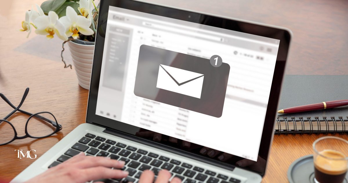 A person types on a laptop at a desk, with everyday work essentials nearby, illustrating a modern workspace. This image supports the topic of email deliverability and highlights the importance of email authentication in 2024 to keep marketing emails out of spam folders.