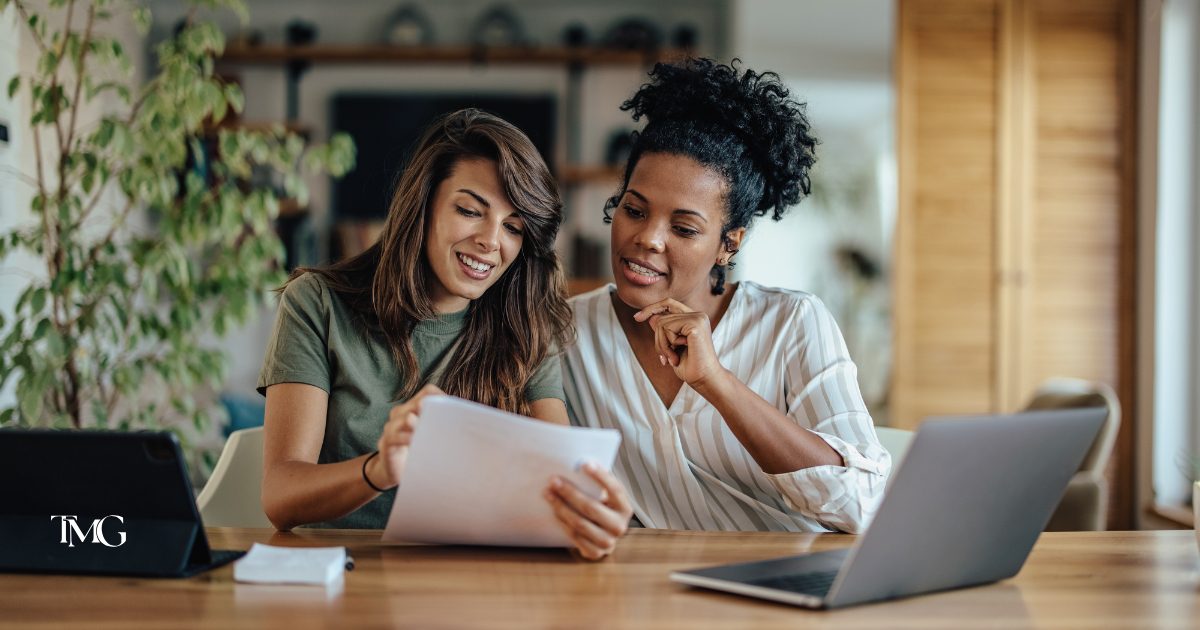 Team collaborating and smiling while reviewing a marketing strategy playbook on a laptop during a planning session.