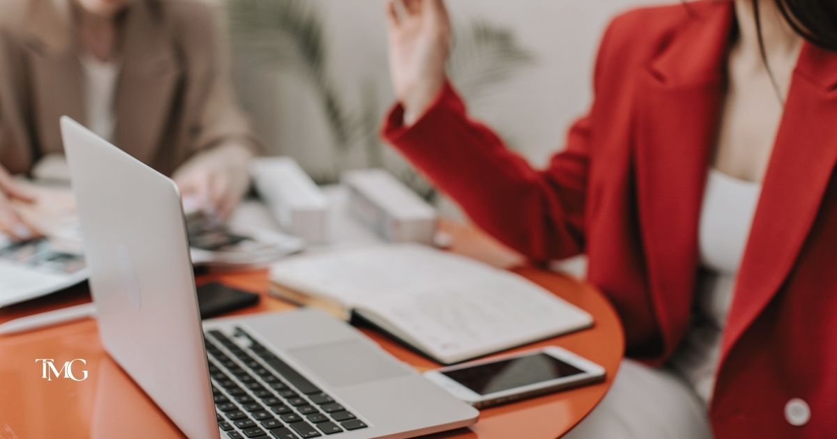 Close-up of a creative team working at a laptop with notebooks and marketing materials, representing collaborative UX/UI brand strategy development.