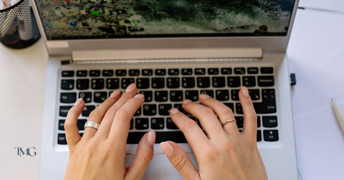 Close-up of a person’s hands typing on a laptop keyboard, representing work on website accessibility and accessible web design by TMG Marketing Partners; nearby office items hint at efforts toward website ADA compliance and accessibility compliance.