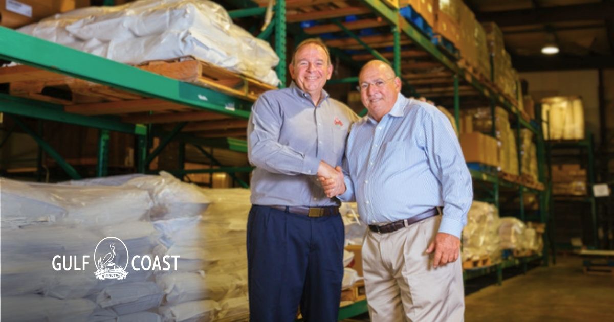 Two Gulf Coast Blenders team members shaking hands in a warehouse, reflecting partnership, supply chain trust, and brand authenticity.