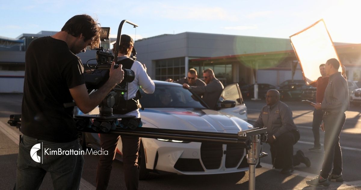 Behind-the-scenes photo of Kim Brattain Media video production team filming a professional car shoot at sunset.