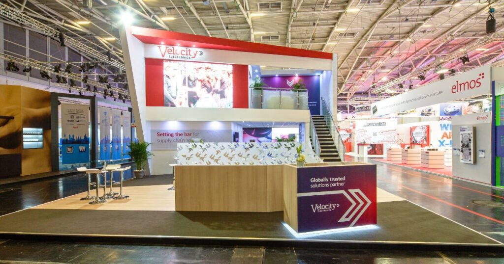 High-impact two-level booth design with bold branding for Velocity Electronics
