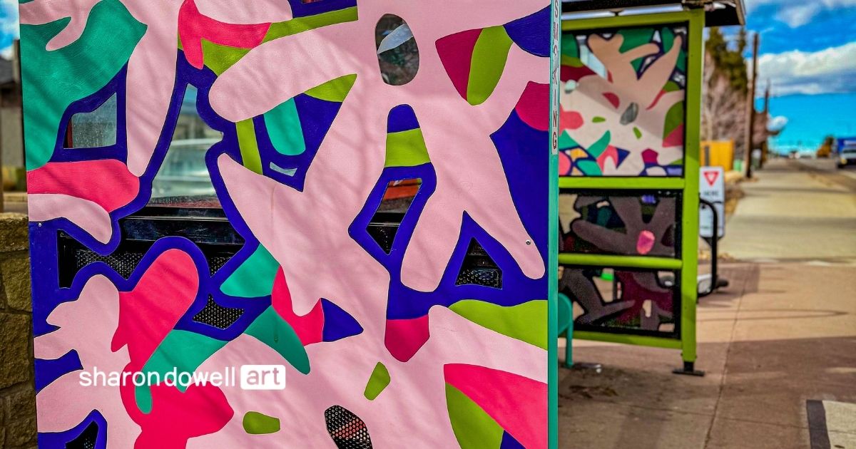 Colorful abstract bus shelter panels designed by artist Sharon Dowell, featuring bold organic shapes in pink, green, blue, and red. The layered cut-out style adds depth and transforms everyday infrastructure into vibrant visual storytelling.