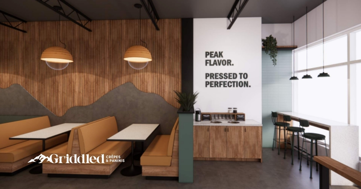 Griddled interior with cozy booth seating and bold restaurant branding message on the wall: “Peak Flavor. Pressed to Perfection."