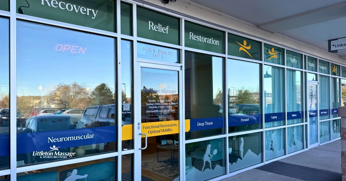 Close-up of Littleton Massage’s storefront windows featuring neuromuscular and deep tissue services with branded visual design elements.