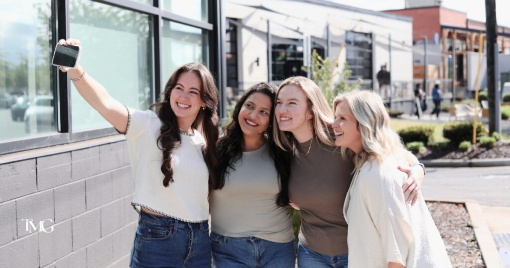 A team of four women smiling and taking a selfie outside a business location—representing teamwork behind Google Business Profile optimization and a strong local SEO strategy.