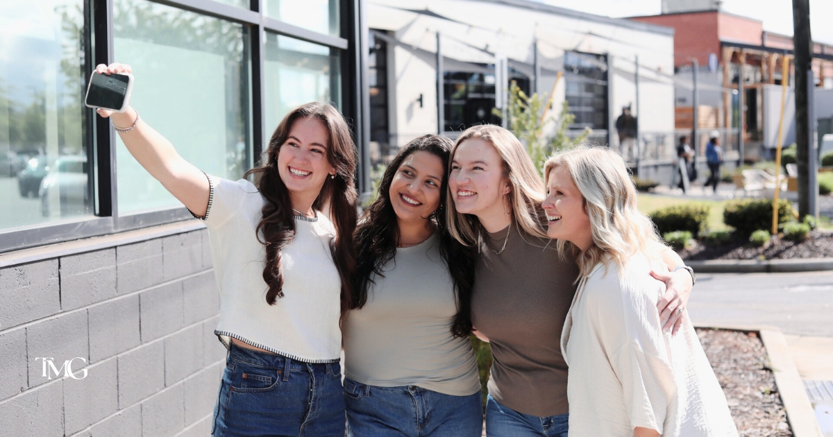 A team of four women smiling and taking a selfie outside a business location—representing teamwork behind Google Business Profile optimization and a strong local SEO strategy.
