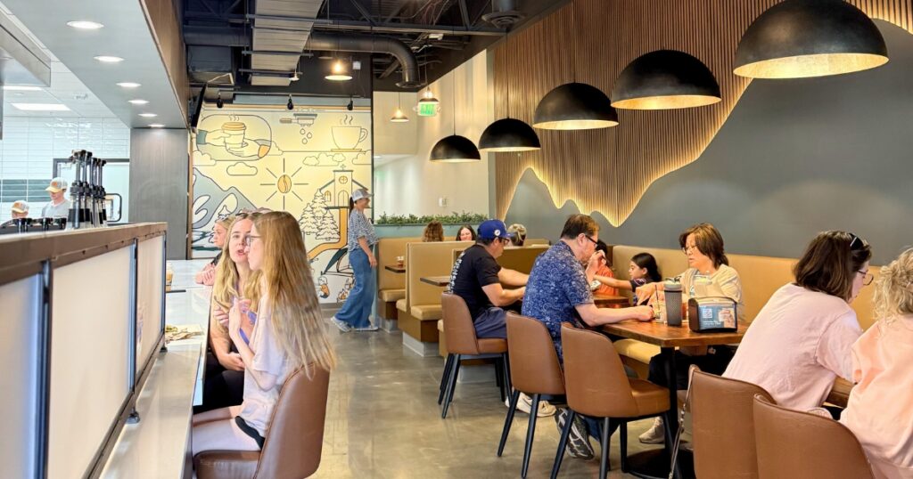 Diners sit beneath a mountain-themed mural and pendant lighting in the Griddled Crêpes & Paninis dining room.
