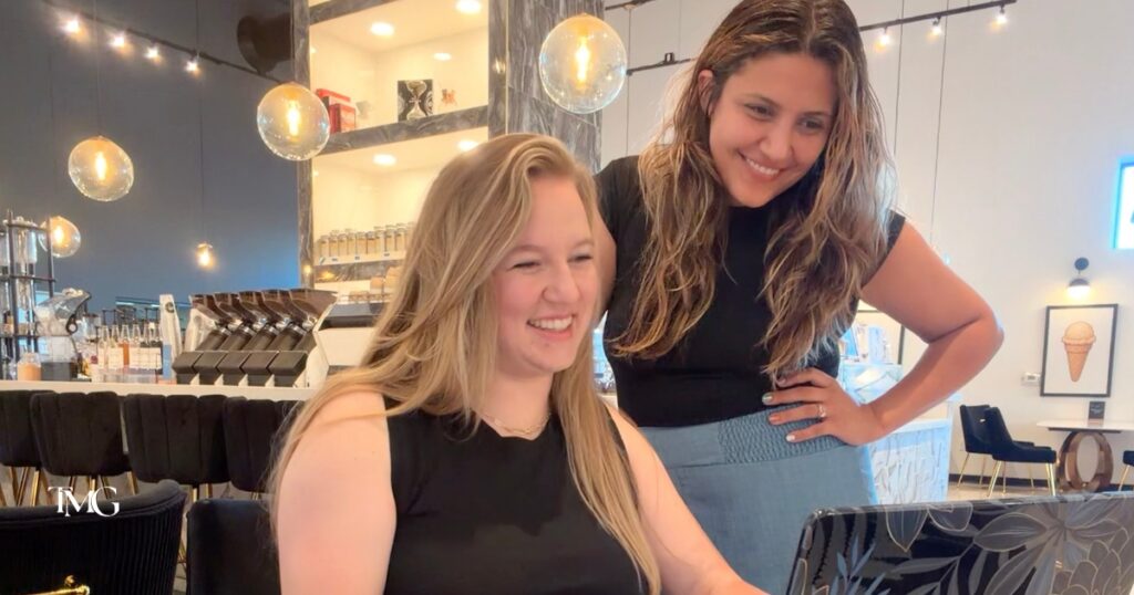 Lilia and Giselle from TMG smiling together over a laptop, reflecting the strong business relationships behind this Colorado marketing agency.