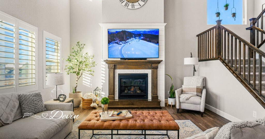 Bright living room with a shiplap fireplace, tufted leather ottoman, and wood staircase, featured on the Homes with Devin realtor website