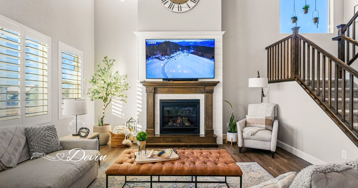 Bright living room with a shiplap fireplace, tufted leather ottoman, and wood staircase, featured on the Homes with Devin realtor website